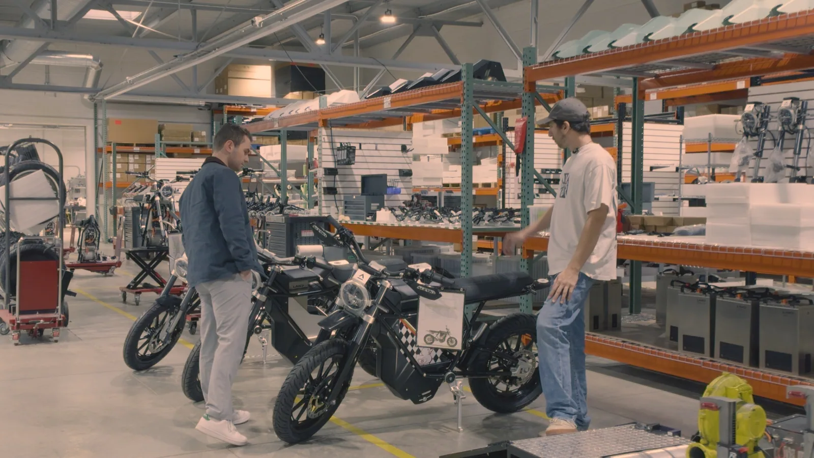 Two people discussing an electric motorcycle on a factory floor