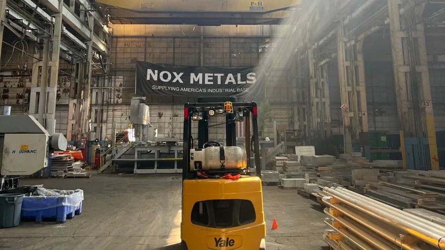 Nox Metals facility with a forklift and banner reading 'Supplying America's industrial base'